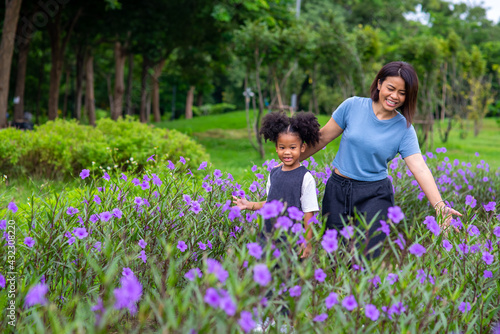Happy mixed race family in park. Mother with little daughter holding hand and walking together in the garden. Mom and child girl kid enjoy and having fun in summer outdoor activity weekend vacation