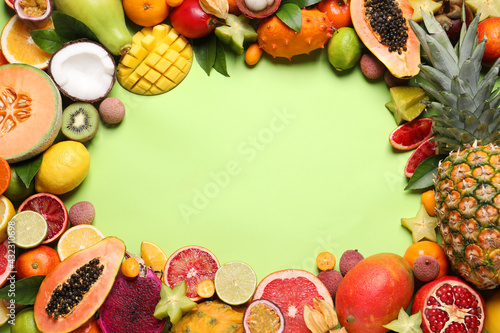Frame of different exotic fruits on green background, flat lay. Space for text