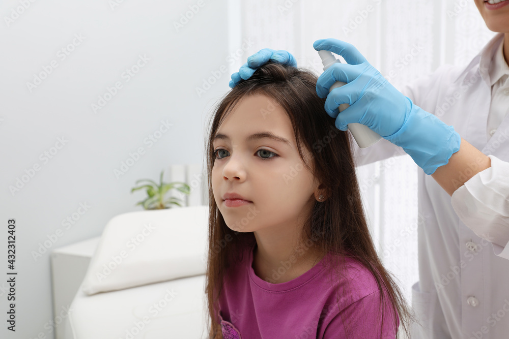 Doctor using lice treatment spray on little girl's hair indoors Doctor using lice treatment spray on little girl's hair indoors