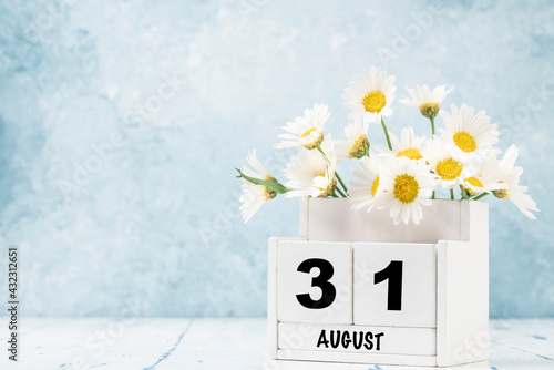 cube calendar for August with daisy flowers over blue photo