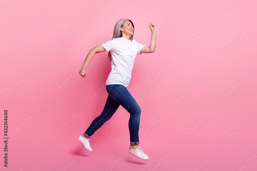 Full length body size view of lovely cheerful grey-haired woman jumping running isolated over pink pastel color background Full length body size view of lovely cheerful grey-haired woman jumping running isolated over pink pastel color background