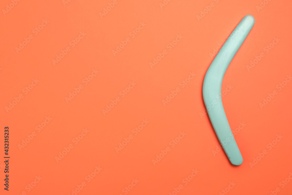 Turquoise boomerang on orange background, top view. Space for text Turquoise boomerang on orange background, top view. Space for text