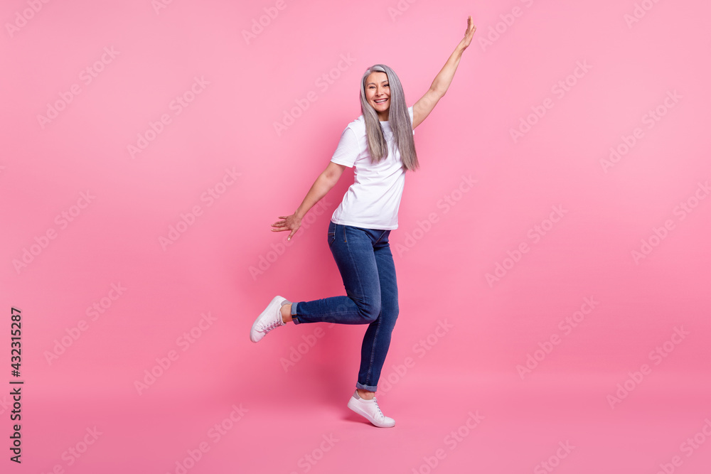 Full length body size view of attractive cheerful grey-haired woman dancing having fun isolated over pink pastel color background