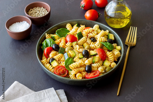 Pasta salad with tomatoes, zucchini, olives and spinach. Healthy eating. Vegetarian food.