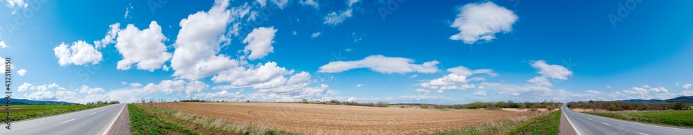 Panorama of plowed field in spring on a background of green mountains
