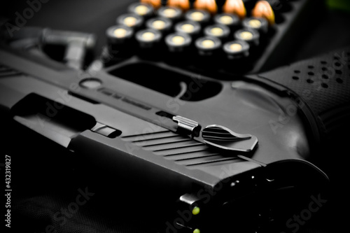 Automatic black 9mm pistol and bullets on black leather background, selective and soft focus.