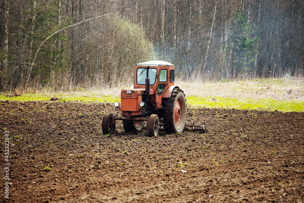 a tractor plows a field. preparation of agricultural land for planting. a mechanical plow makes furrows in the soil. cultivation of fertile land a tractor plows a field. preparation of agricultural land for planting. a mechanical plow makes furrows in the soil. cultivation of fertile land