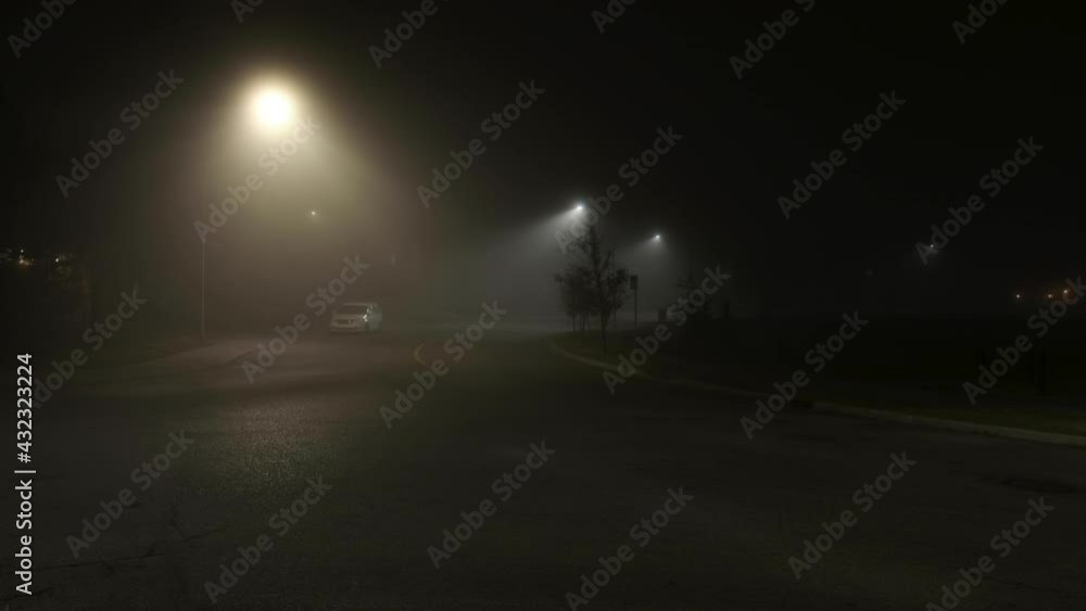 Lights illuminate thick ethereal fog on empty city street at night Lights illuminate thick ethereal fog on empty city street at night