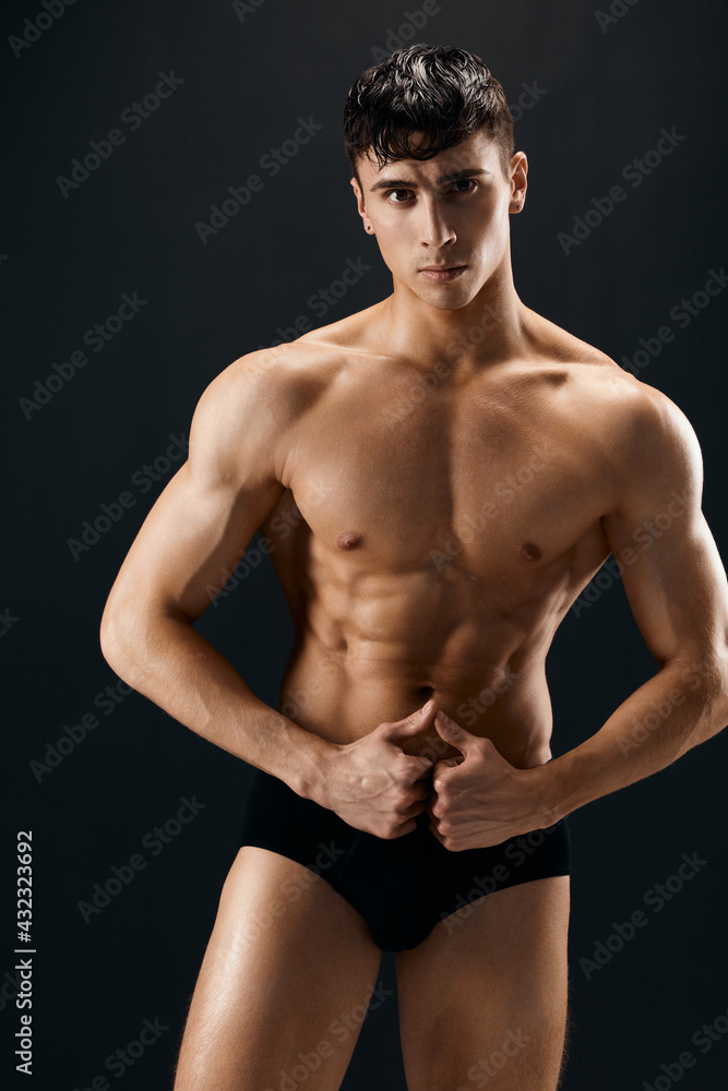 handsome man with muscular body in dark in shorts posing isolated background handsome man with muscular body in dark in shorts posing isolated background