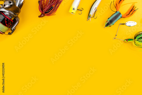Bass fishing concept on the yellow trendy background. Flat lay style. Fishing tackle, soft silicon lures, spinner bait and wobblers. 