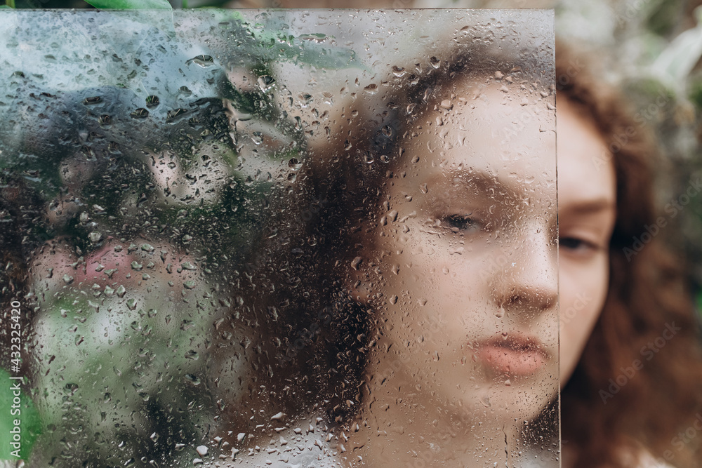 Close up woman art portrait with soft focus look through glass with drops
