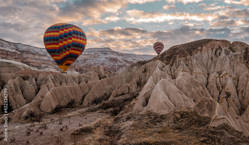 Beautiful panorama view of hot air balloons flying in Cappadocia, Turkey at sunrise with typical rock formations and fairy chimneys