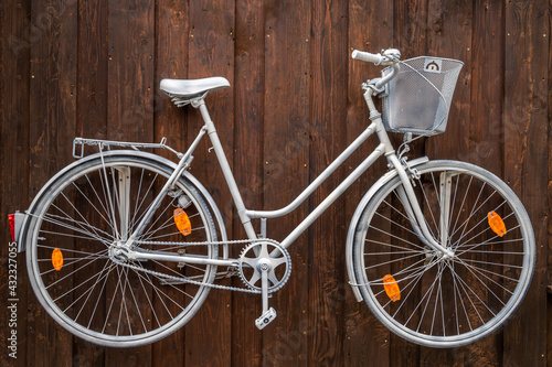 Kreative Wandgestaltung mit einem alten weiß lackierten Fahrrad an einer Holzwand