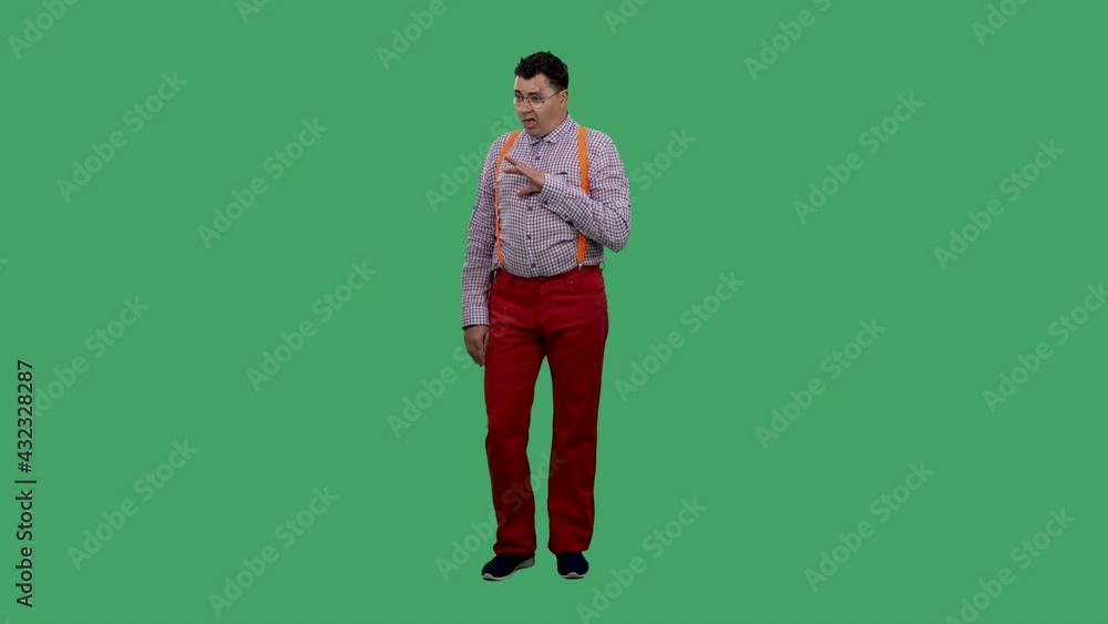 Bored man showing blah blah blah gesture. He listens to lies, nonsense, empty promises. Portrait of a man in glasses, a plaid shirt with orange suspenders in the studio on a green screen. Slow motion. Bored man showing blah blah blah gesture. He listens to lies, nonsense, empty promises. Portrait of a man in glasses, a plaid shirt with orange suspenders in the studio on a green screen. Slow motion.