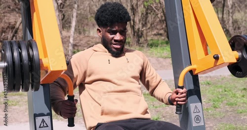 African american man doing chest exercise on pec dec fly machine at park photo