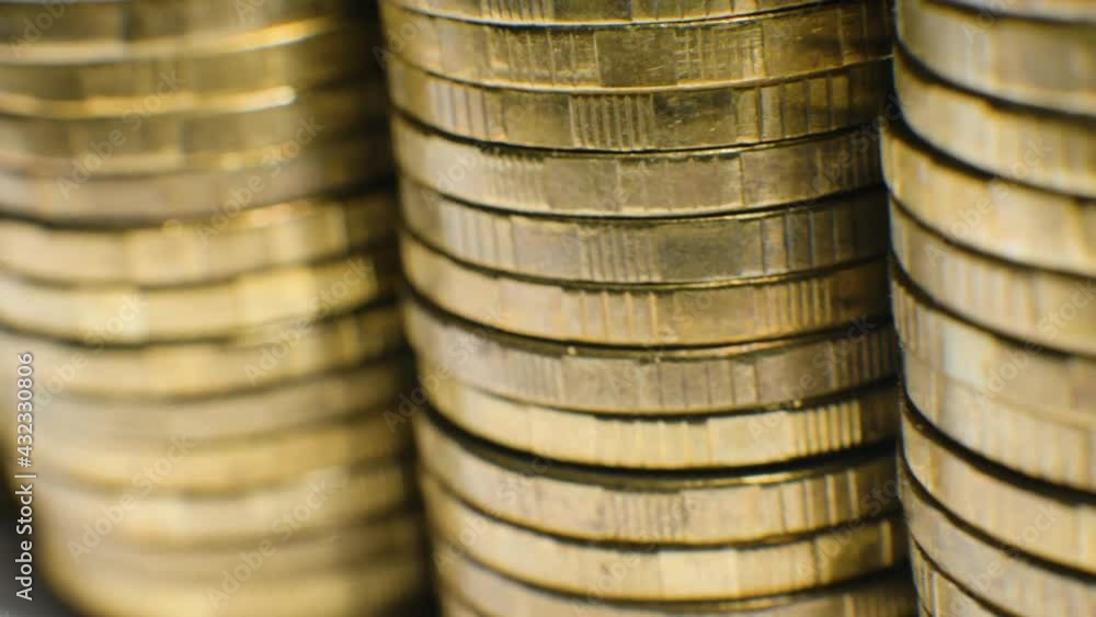 Numerous weathered shiny golden solid metal coin piles stacked in alignment on blurred white table extreme close view Numerous weathered shiny golden solid metal coin piles stacked in alignment on blurred white table extreme close view