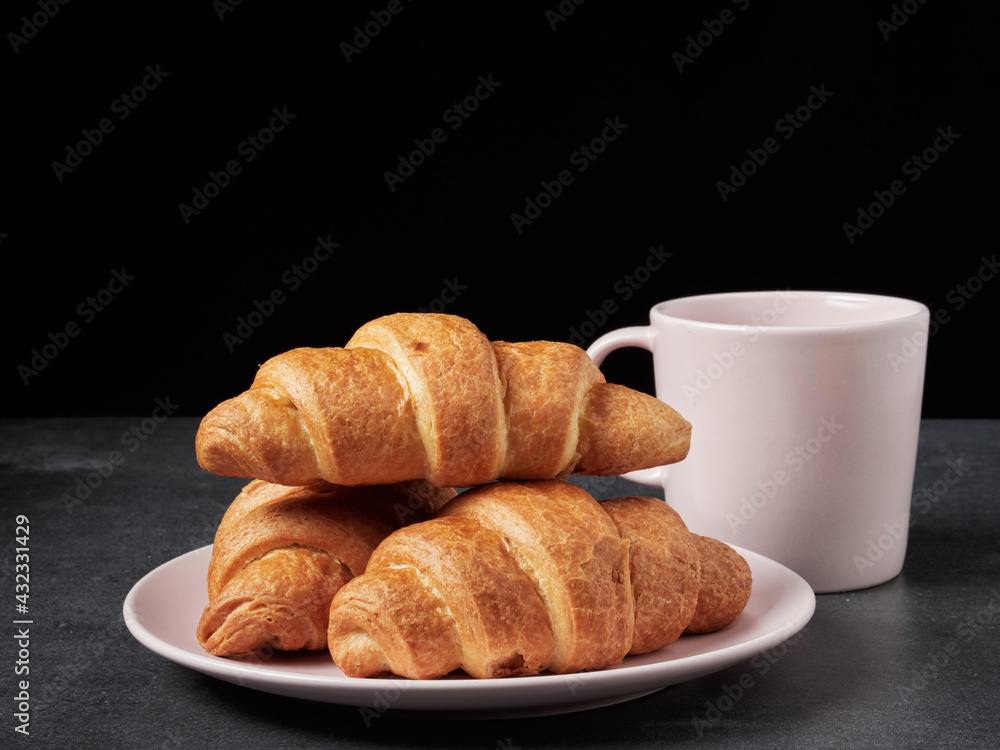 baked french croissants on a brown kitchen board, black background, close-up