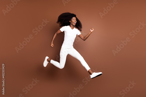 Full length body size view of attractive cheerful motivated girl jumping running isolated over brown color background