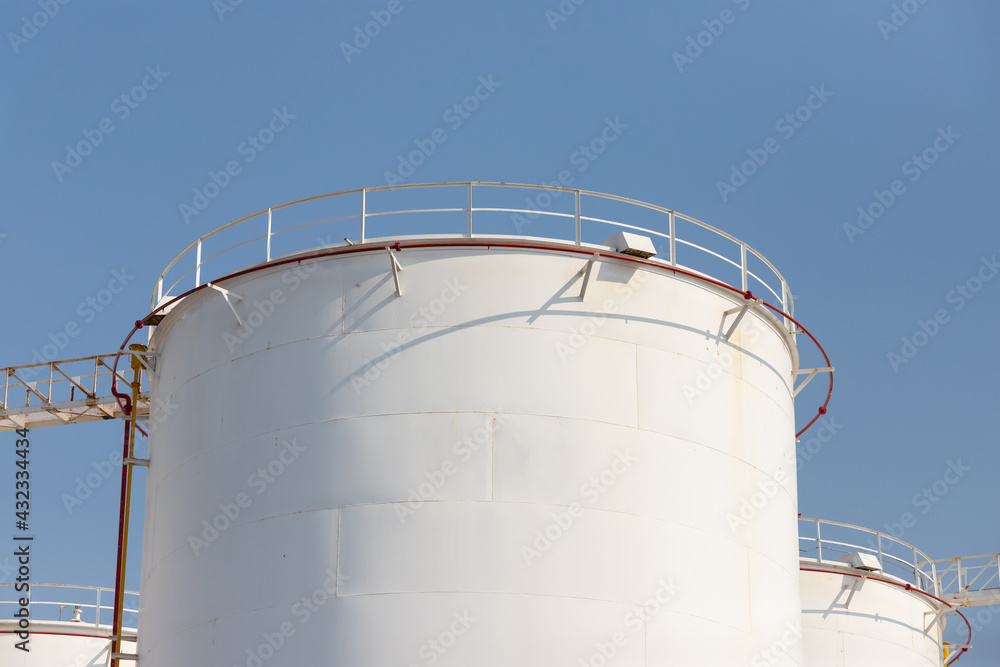 white petroleum steel tanks against blue sky, white metal silo with rust, liquid metal container. white petroleum steel tanks against blue sky, white metal silo with rust, liquid metal container.