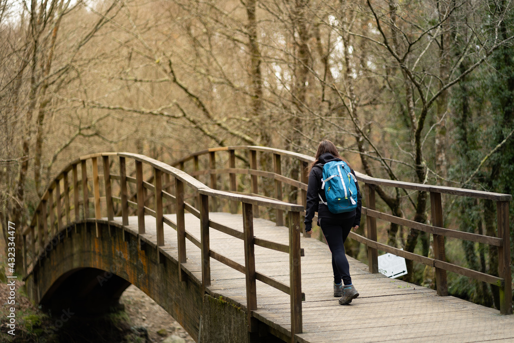 Woman crossing a bridge, with backpack. Lifestyle and nature concept