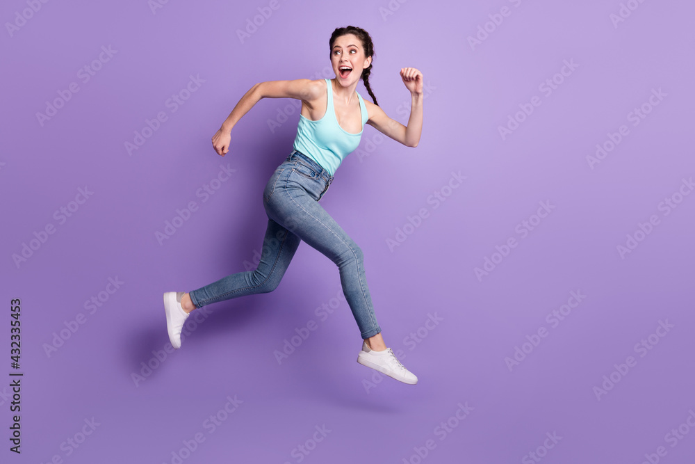 Full body profile photo of cheerful lady run look back wear top jeans isolated on purple color background Full body profile photo of cheerful lady run look back wear top jeans isolated on purple color background