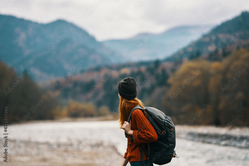 woman in a hat with a backpack are resting in the mountains in nature near the river woman in a hat with a backpack are resting in the mountains in nature near the river