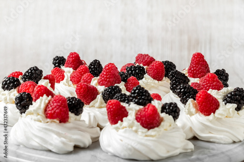 Pavlova s cake on a marble stand. Cake with meringues  raspberries and blackberries. High quality photo