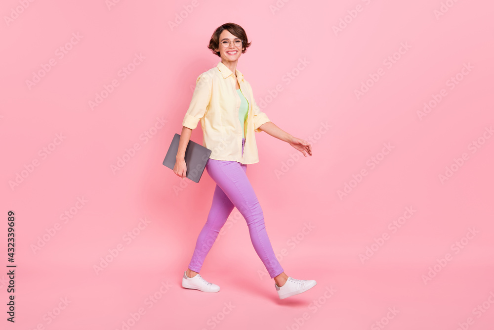 Photo of adorable young lady dressed yellow shirt spectacles walking holding modern gadget isolated pink color background Photo of adorable young lady dressed yellow shirt spectacles walking holding modern gadget isolated pink color background