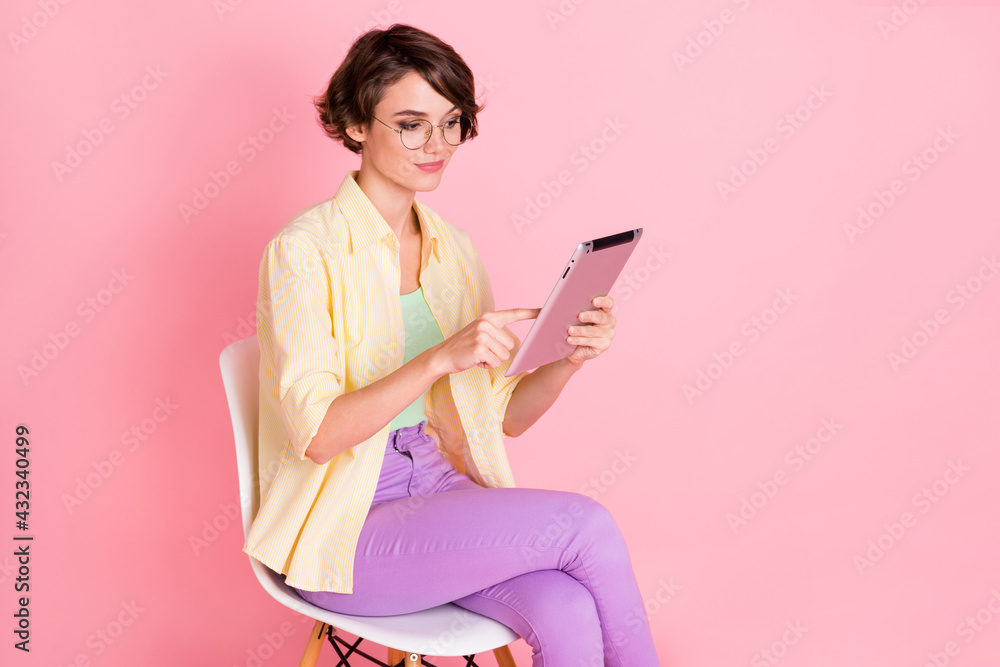 Photo of cute shiny woman wear yellow shirt glasses sitting chair writing papers looking empty space isolated pink color background Photo of cute shiny woman wear yellow shirt glasses sitting chair writing papers looking empty space isolated pink color background