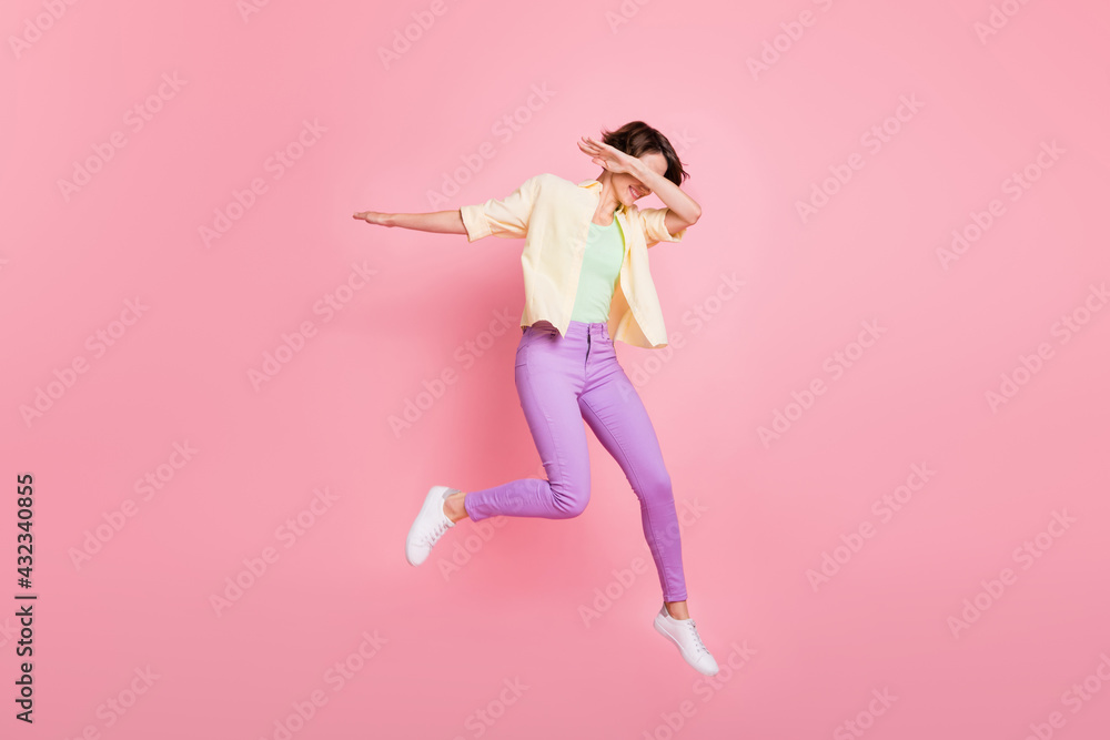 Full size profile photo of optimistic brunette lady jump dance dab wear shirt trousers sneakers isolated on pastel pink background Full size profile photo of optimistic brunette lady jump dance dab wear shirt trousers sneakers isolated on pastel pink background