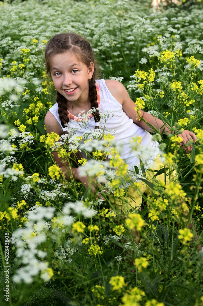 beautiful smiling girl in a flower field among white and yellow flowers on a sunny summer day. Children and nature beautiful smiling girl in a flower field among white and yellow flowers on a sunny summer day. Children and nature