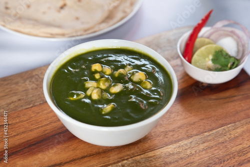 Closeup of a bowl of fresh corn palak on a wooden board on the table photo