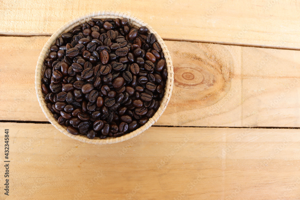 Coffee beans in the wicker basket isolated on wooden background closeup. Coffee beans in the wicker basket isolated on wooden background closeup.