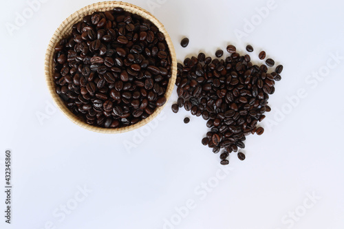 Coffee beans in the wicker basket and pile isolated on white background closeup.