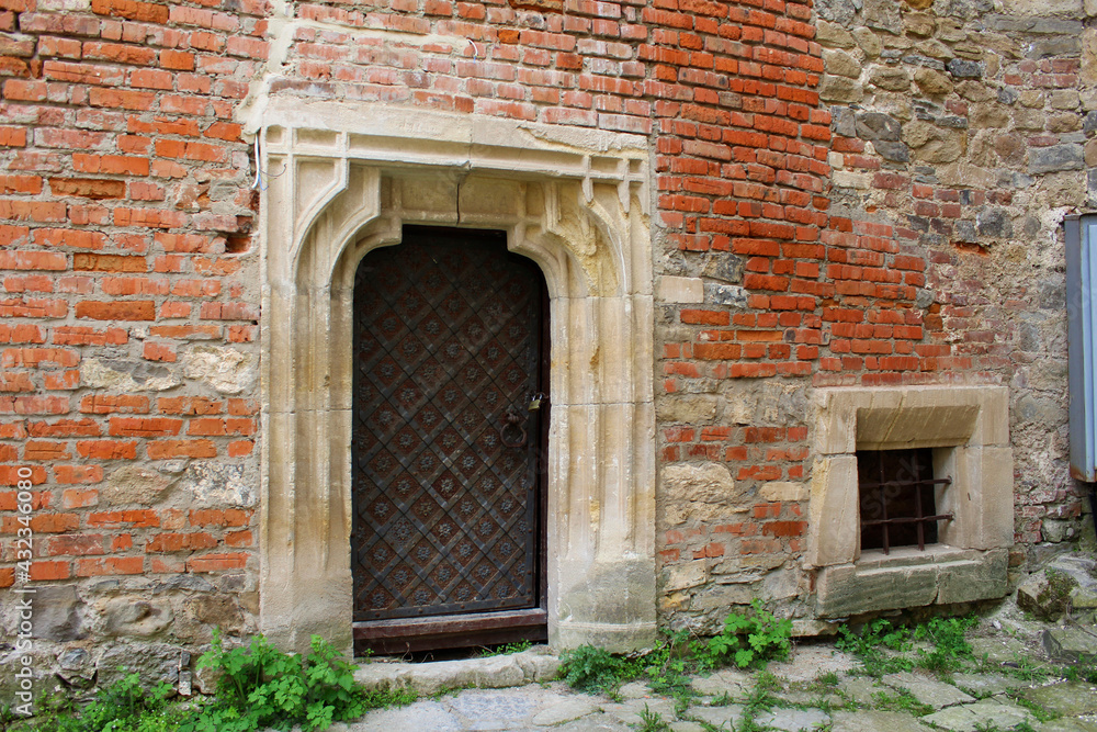 Old metal doors in a brick and stone building with a grate on the window. Old metal doors in a brick and stone building with a grate on the window.