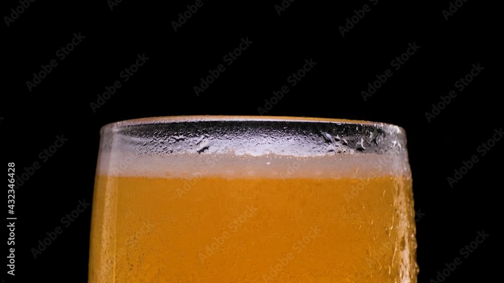 Beer with bubbles and foam in a glass on black background. Beer with bubbles and foam in a glass on black background.
