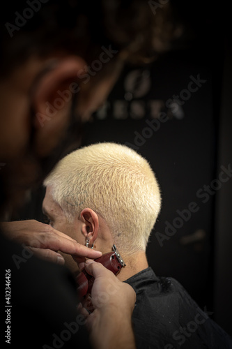 barber's hands cutting and painting head as a young man in vintage barbershop  photo