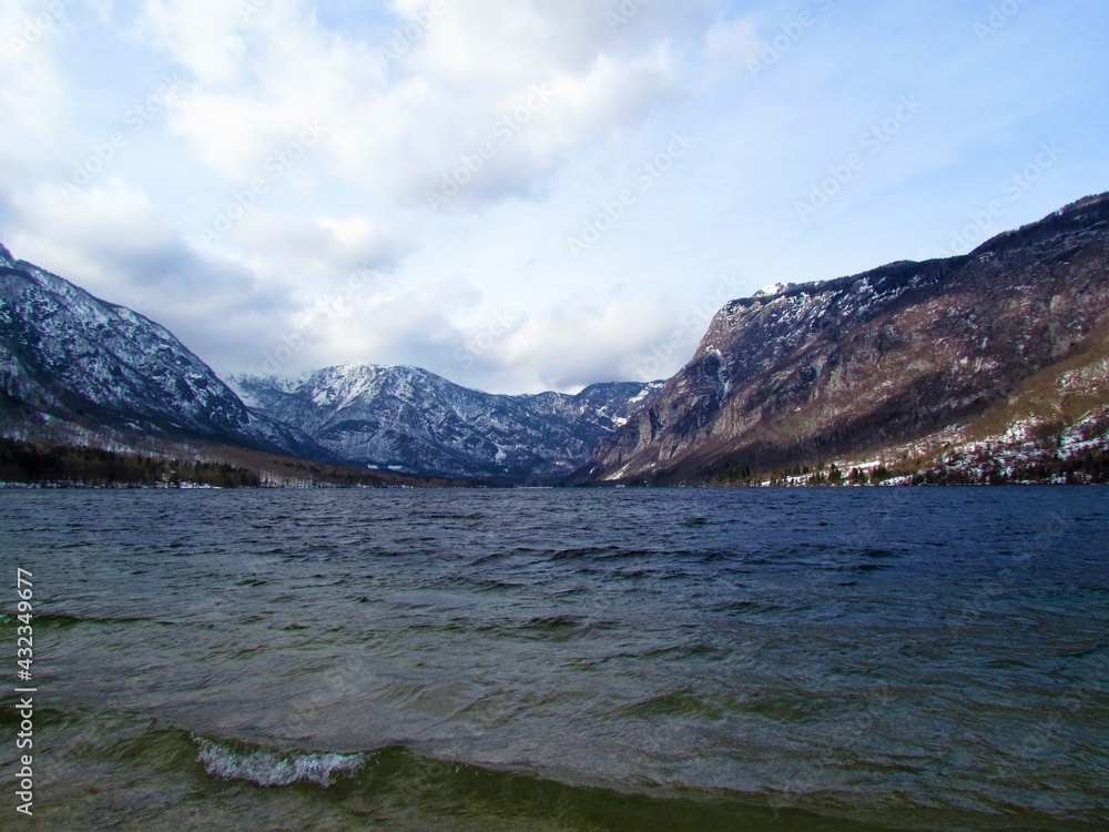View of Bohinj lake in Gorenjska, Slovenia with snow covered mountains of the Julian alps behind in winter