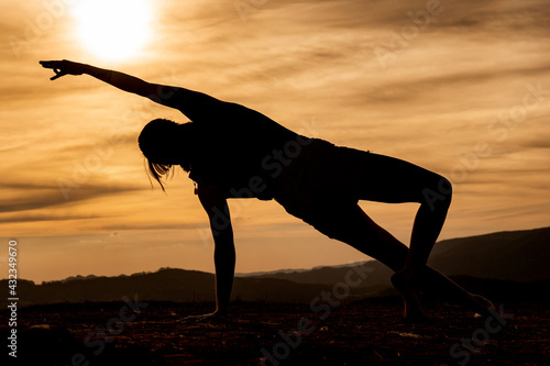 Fototapeta Naklejka Na Ścianę i Meble -  Silhouette of a  young woman practicing yoga alone on the mountains with a beautiful sunset