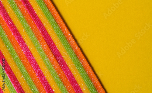 Closeup of bright tasty sour sweet candy texture, background yellow photo