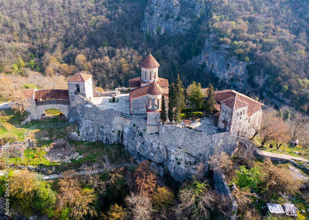 Picturesque aerial view of Georgian Orthodox Motsameta monastery on stone cliff covered with forest located near Kutaisi at Imereti region on sunny spring day