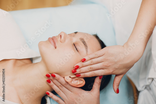 Beautiful young woman getting face treatment massage at beauty spa
