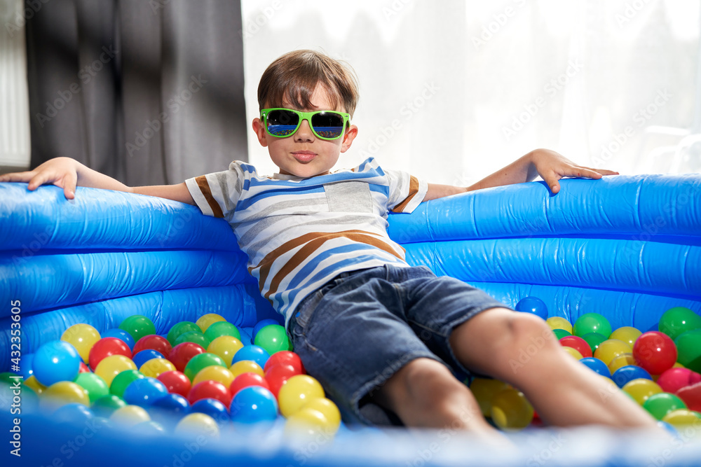 Obraz premium Portrait of relaxed boy in an inflatable ball pool