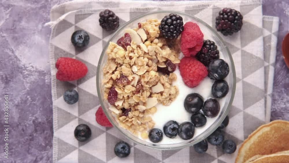 Granola and berries in bowl on pink background Granola and berries in bowl on pink background