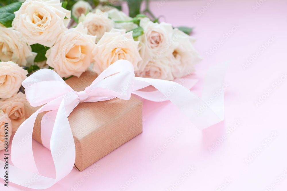 Gift box wrapped in brown paper with pink roses on pink background. Gift box wrapped in brown paper with pink roses on pink background.
