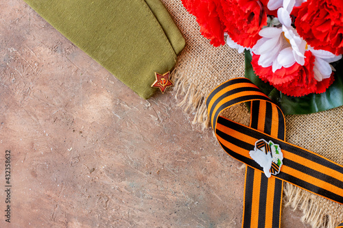 Concept background of May 9 russian holiday Victory Day. Red carnations, St. George's ribbon and order of the Red Star. On brown background, copy space