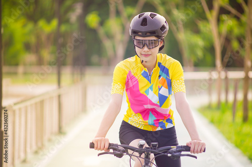 Portrait image of Young Asian cyclist girl wearing helmet cycling and yellow shirt riding bike, healthy lifestyle concept.