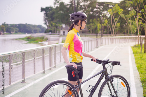 Young Asian cyclist take a rest after cycling on bike path, healthy lifestyle concept.