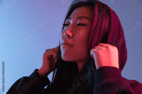Portrait of Asian young woman isolated gradient colors studio background in neon. Concept of human emotions.