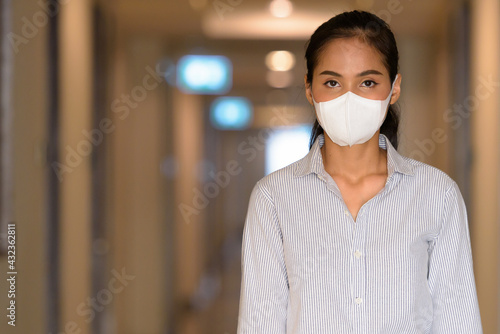Asian woman wearing face mask to protect from coronavirus Covid-19 at apartment hallway